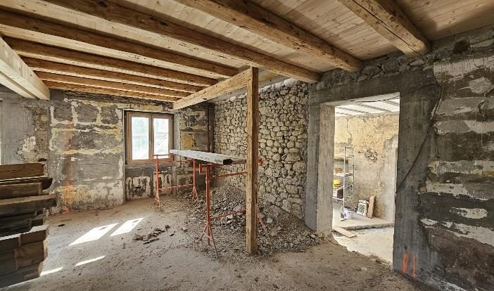 Maison en pierre avant rénovation : murs bruts et poutres apparentes
